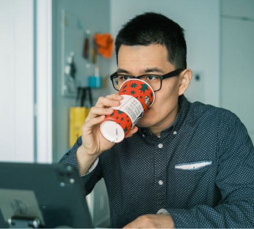 male working at a desk drinking 